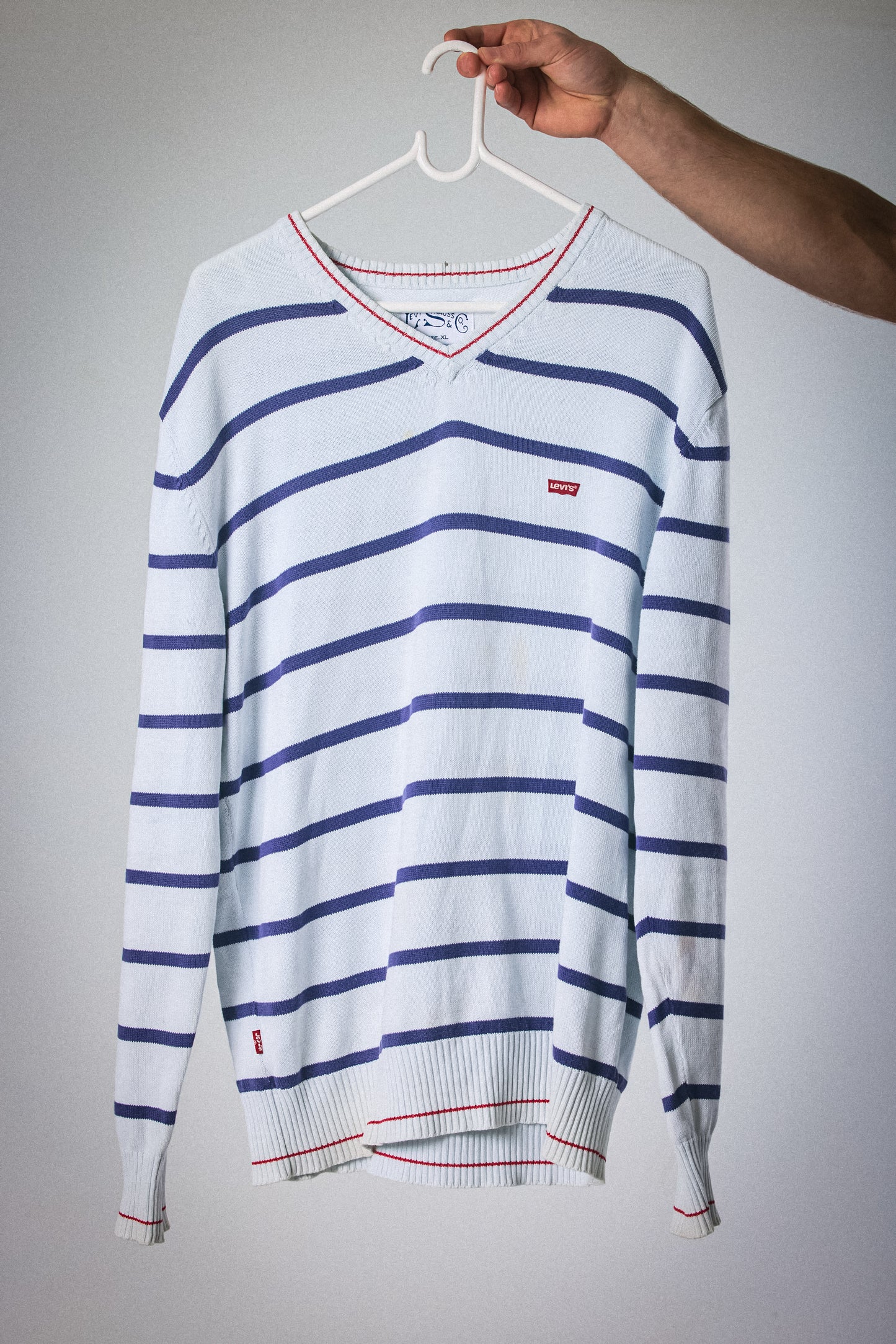 Striped sweater on a hanger against a plain background