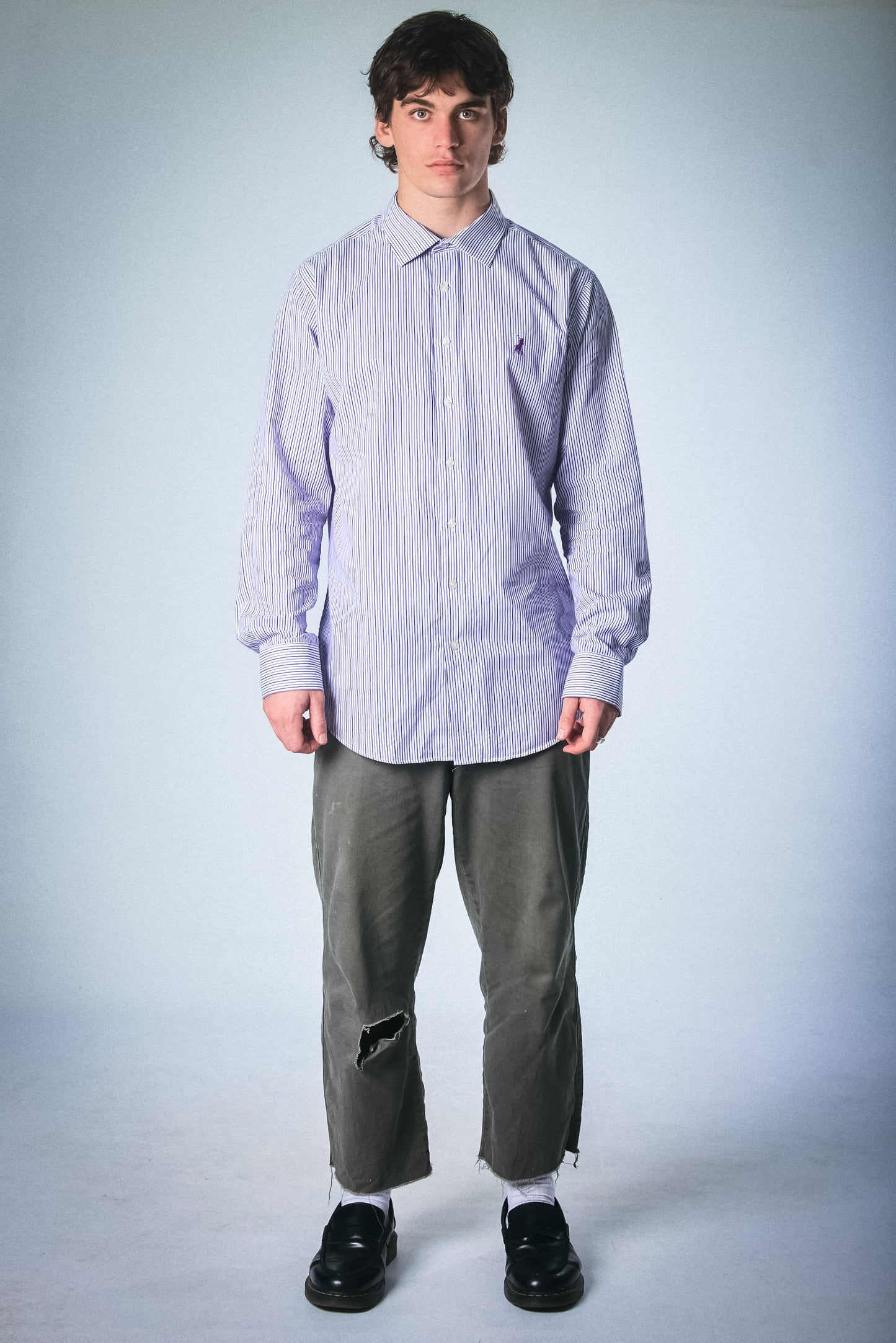 Person wearing a light purple Polo striped shirt and gray pants on a white background