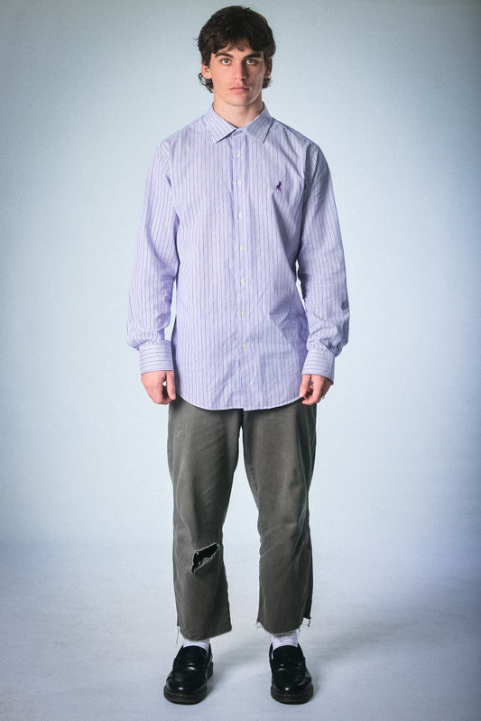 Person wearing a light purple Polo striped shirt and gray pants on a white background
